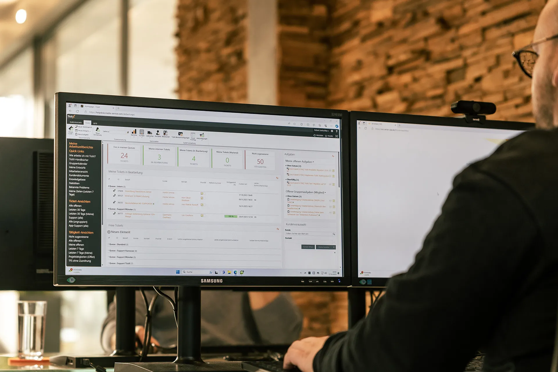Mitarbeiter am Arbeitsplatz mit dem TickX-Dashboard auf zwei Monitoren