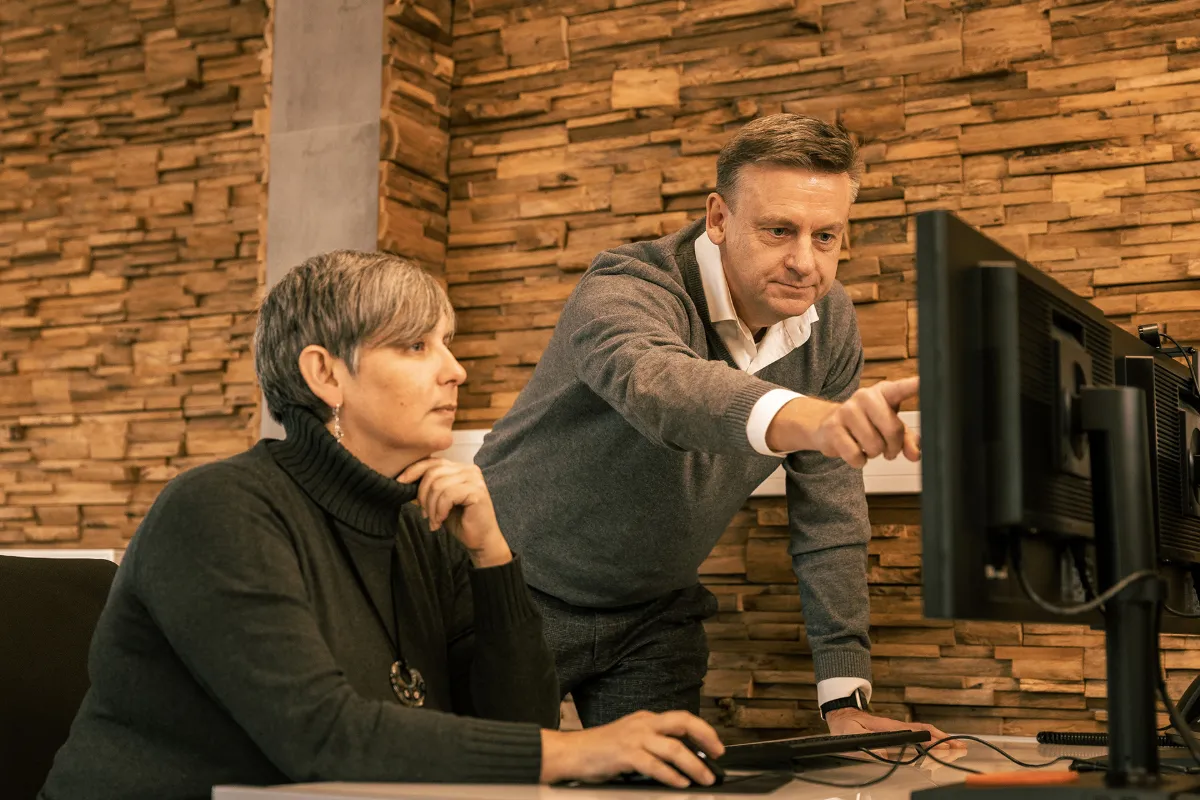Zwei Kollegen besprechen Inhalte auf einem Monitor